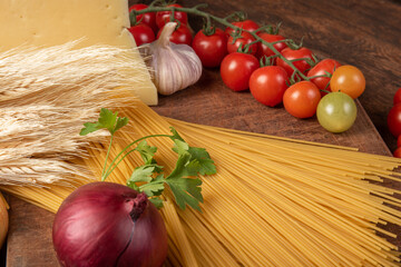 Italian pasta (macaroni), spaghetti, tomatoes, olive oil, cheese and spices on rustic wood, selective focus.
