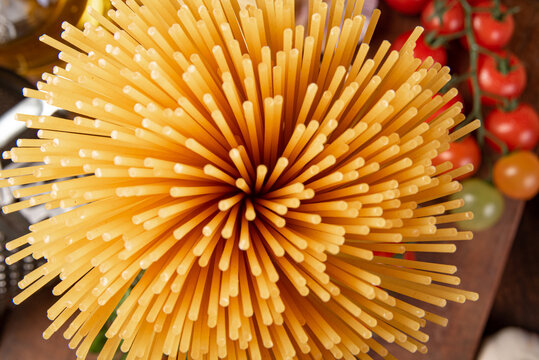 Italian Pasta (macaroni), Spaghetti Tied With Sisal String, Tomatoes, Olive Oil, Cheese And Spices On Rustic Wood, Top View.