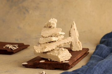 Sunflower halva on a wooden board and a light background with blue textiles. Natural vegan product. Eastern sweetness. Rustic style.