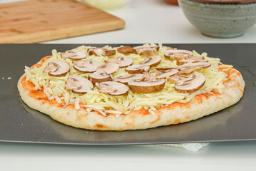 Raw pizza dough with tomato sauce, mozzarella, and Crimini mushroom slices. Step by step baking process, recipe