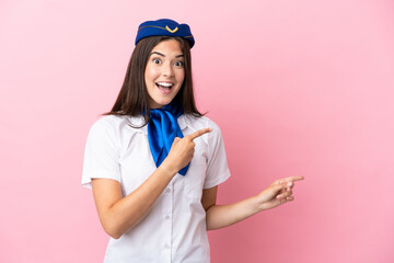 Airplane stewardess Brazilian woman isolated on pink background surprised and pointing side