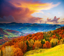 Magical view of the evening mountains with yellow and red trees on the slopes.