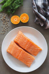 Fillets of salmon in white plate side with orange, black pepper and dill. Salmon is delicious and healthy fish. Salmon is famous in the world it can use in western food and eastern food.