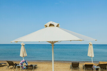Beautiful landscape view of empty sunbeds under umbrellas on sand beach. Greece. 