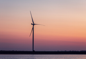 Background of the windmill on the shore at the sunset; colors of the sky are soft gradient
