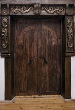 An antique dark wood door in the vertical photo. Rough powerful door reliably closing the passage