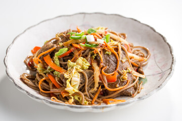 Soba noodles with beef, carrots, onions and sweet peppers isolated on white background