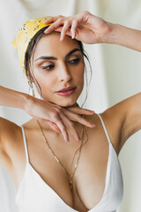 stylish woman in yellow headscarf and crop top posing while looking away on white - obrazy, fototapety, plakaty
