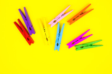 Colorful wooden clothespins on yellow background. Close up, copy space. Minimalism, original and creative photo. Be another. Individuality concept.
