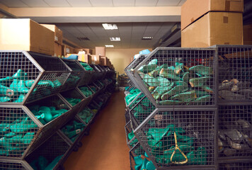 Aisle between rows of storage containers full of shoe form lasts and cardboard boxes with footwear...
