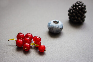 Blueberry, blackberry and red currant on gray background. Fresh ripe berries. Berries in row with copy space. Vitamin and antioxidant concept. Organic food. Healthy nutrition. Sweet berries in studio.