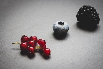 Blueberry, blackberry and red currant on grey background with vignette. Fresh ripe berries. Berries in a row. Vitamin and antioxidant concept. Organic food. Healthy nutrition. Sweet berries in studio.
