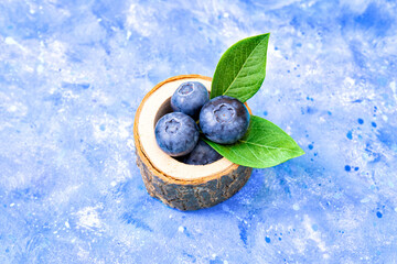 Hand made stump bowl with blueberries on a blue background