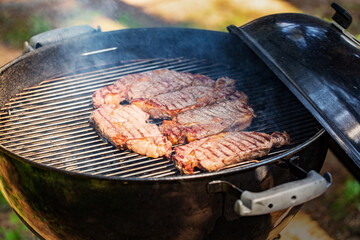 Cooking marbled beef steak on a charcoal grill. The meat is fried on coals with smoke
