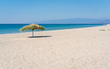 Beach umbrela on sandy beach, mediterranean sea, Calabria Italy.
