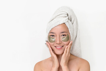 beautiful young Asian woman after spa treatments with a towel on her head with patches under her eyes. the concept of skin care, preserving youth