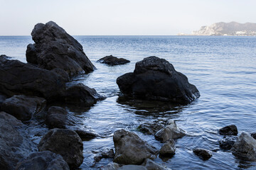 clear sea water washing the stones at the foot of the mountain