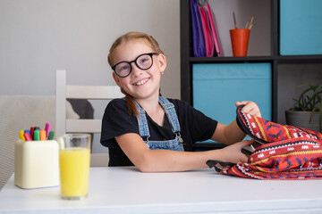 Cute happ redhead girl packing backpack, preparing for school