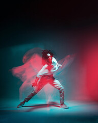 Contemporary hip hop dance. Cool dancing modern girl moving in colorful neon studio light. Long...