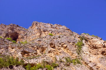 Fototapeta na wymiar A high rock overgrown with grass against the blue sky.
