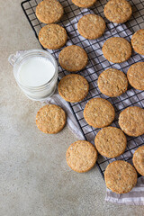 Healthy oatmeal cookies with cereals, seeds and nuts with a cup of milk on concrete background. Diet vegan cookies.