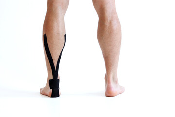 Kinesiology taping treatment with black tape on male patient injured Achilles tendon. Sports injury kinesio treatment.