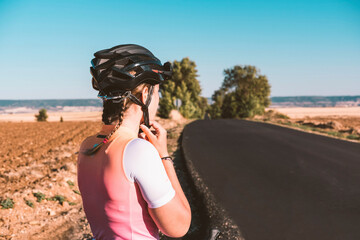 Young female cyclist putting on a cycling helmet. Cycling concept. Sport concept.