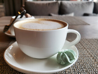 White ceramic cappuccino cup with turquoise meringues on a saucer