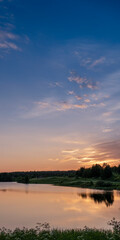 Obraz premium Beautiful sky sunset on a calm lake surrounded by forest in the taiga. Vertical format.