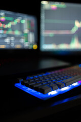 Blue keyboard with two monitors showing the Binance trading platform in the background