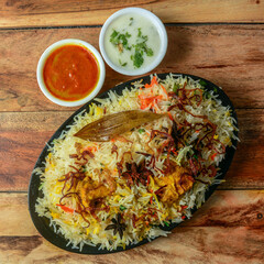 Traditional Hyderabadi Chicken dhum Biryani made of Basmati rice cooked with masala spices, served with raita, selective focus