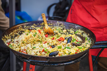 Large frying pan with cooked Spanish paella with seafood. Outdoors food, barbecue, Street food...