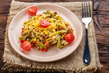 Risotto with mushrooms in a plate on a wooden background on a linen napkin and fork.