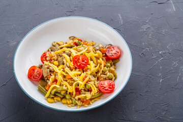 Risotto with mushrooms and cheese and vegetables in a plate on a gray background.