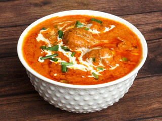 Malai Kofta Curry - classic North Indian vegetarian recipe alternative to meatballs served with tandoori roti or indian bread, served in a white bowl over a rustic wooden table. selective focus