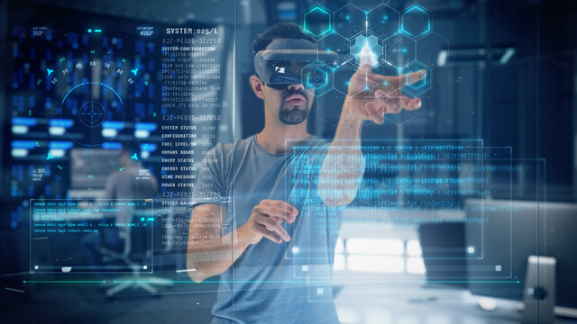 Young man interacting with holographic data inside the Metaverse while using a Virtual Reality Headset. Modern Data Research Facility with Servers.