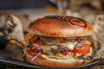 Juicy Beef burger with tomatoes, lettuce, cucumber, melted cheese and onions with grilled bun served on a tray