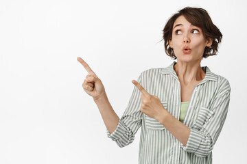 Wow smth interesting. Intrigued brunette girl pointing and looking left, pucker lips curious,...