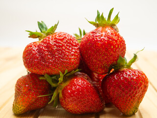 Close-up strawberries with leaves. Ripe red berries lie in a heap on the table. Delicious aromatic berries.