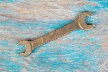 Vintage bronze wrench on shabby background