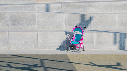 Empty baby stroller on stone steps on a sunny day