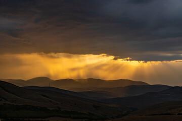 Obraz premium Sunlight filters through the clouds as the sun sets