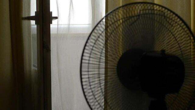 The video shows a close-up of a working fan, only its offices and a curtain stirring from the air are visible.
