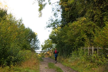 Obraz premium Jogger running along a gravel dirt path on a sunny early autumn morning Riddlesdown Surrey England October 2020