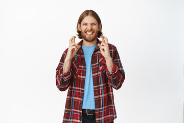 Hopeful lucky guy cross fingers for good luck, smiling excited, waiting for dream come true, making wish, standing against white background