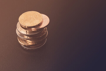 Stack of different euro coins on a black table with free space for text