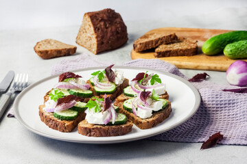 Canapes with toasted bread with sunflower and flax seeds, feta cheese, cucumber and onion