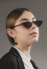 girl in white blouse, black jacket and sunglasses posing