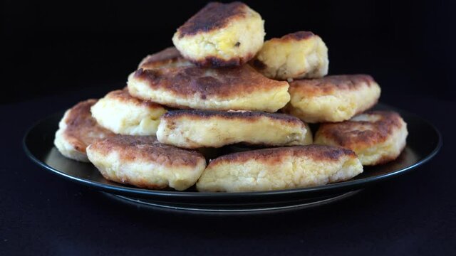 Potato cakes, ukrainian name potato zrazy, stuffed mushrooms or meat or cheese with herbs cream are fried in vegetable oil on black background, close up, rotates. Traditional Ukrainian cuisine
