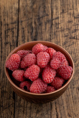 red fresh domestic raspberry at bowl on a rustic table top. space